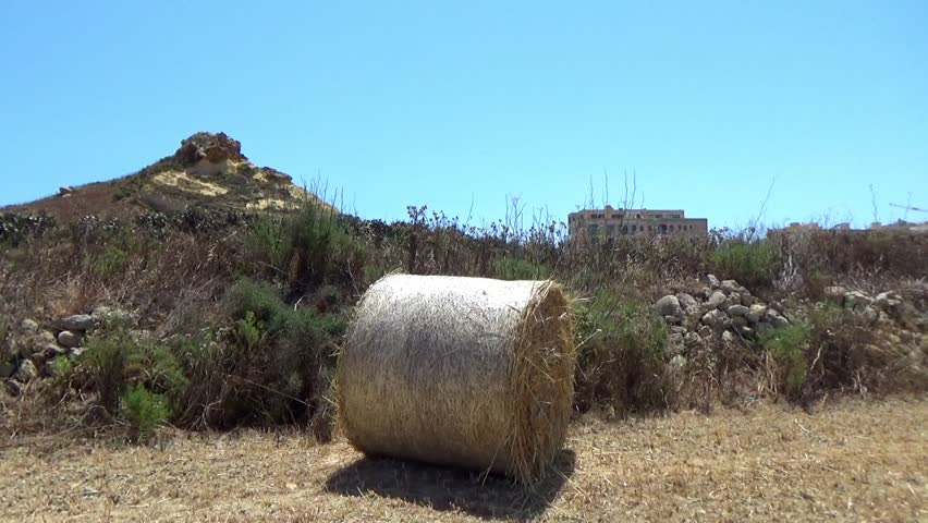 barrel of hay outside with mountain backdrop.