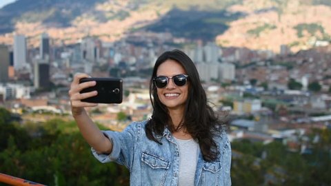 Happy smiling girl with sunglasses taking selfie in front of city panorama, Stunning beautiful smile Caucasian model taking selfie in city park
