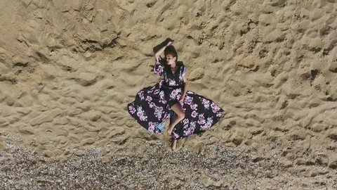 Aerial View. Beautiful Young Woman Is Resting On A Beach. Attractive Girl Lying On The Sand. Gypsy And Maxi Dress Is On The Model. Beautiful Texture In The Sand.