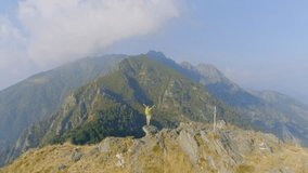 Drone view of female hiking in beautiful mountains and standing arms outstretched celebrating achievement and freedom in nature. People outdoor activities concept 