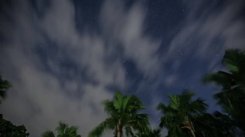 Night Time lapse of Stars with Coconut Trees as clouds passes by in a tropical skies of Bicol Philippines .