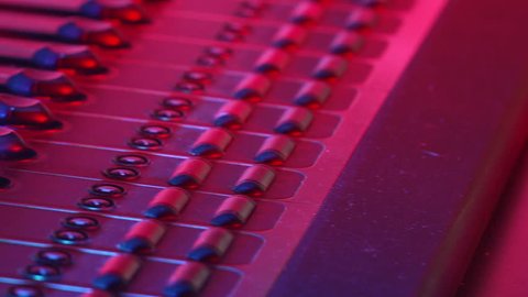 Pan of audio levels on mixer control board in club or modern recording studio