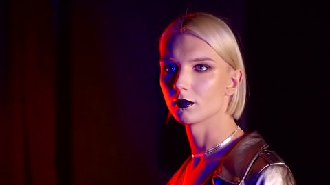 transexual woman with blonde hair and fashion make-up in dark room with colored lights