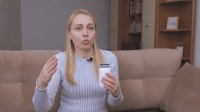 A female blogger writes a vlog and shows a container with dietary supplements