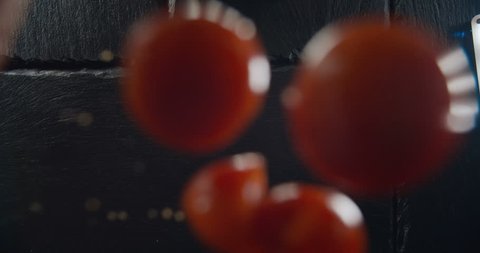 Cherry tomatoes falling and rolling on a table. Shot with high speed camera 4K in slow motion.