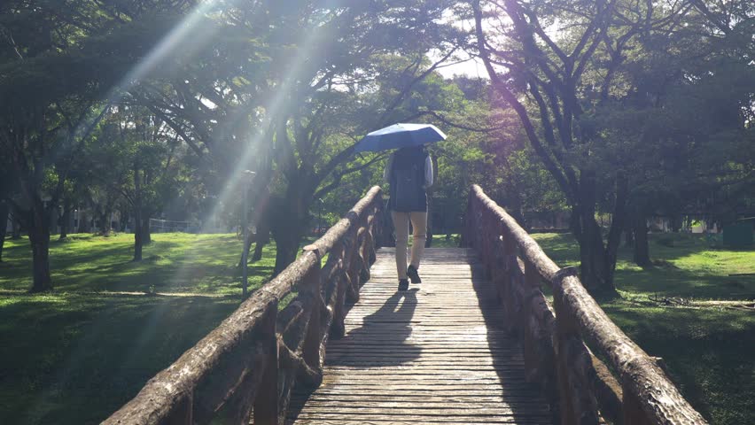 A girl with umbrella walking through the bridge.