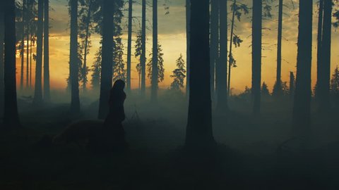 Girl running with a dog in a misty forest, at sunset.