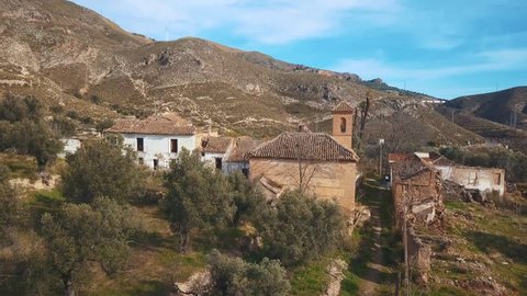 Aerial view of an abandoned village with a church surrounded by nature in Spain.