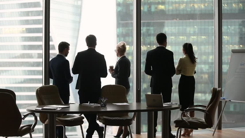 Diverse multi ethnic employees group stand separately talking at work in modern boardroom skyscraper office, racial segregation discrimination prejudice problem at workplace concept, rear back view
 Royalty-Free Stock Footage #1022497324