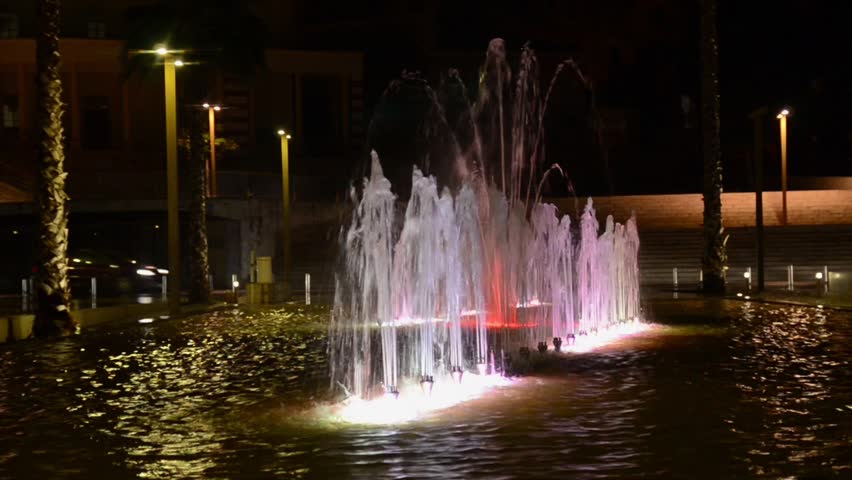 Illuminated and colorful fountain at night. Multi-coloured water jets in fountain pool. Durres, city centre, Albania
