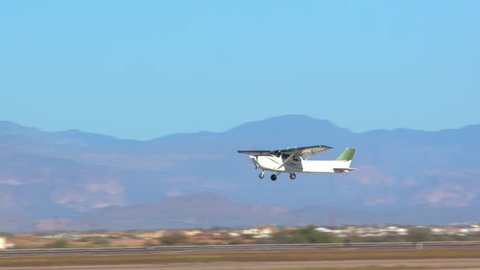 Private Small Generic Airplane Taking Off from Airport Runway with a Blue Layered Mountains Background on a Sunny Day in the Southwest