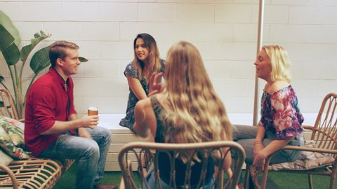 Millennial girl grabs a table out on the patio and greets her friends who come to join her with beers. Medium shot on 4k RED camera. 