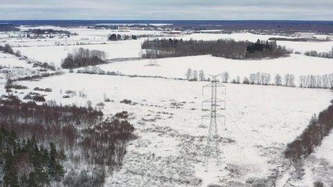 Snowy winter fields with a ultra high voltage power line tower underneath