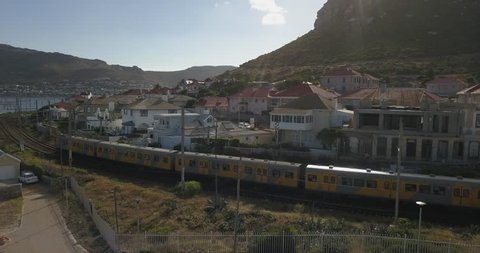 4K aerial drone footage of Kalk Bay busy road traffic and coastal train arriving on sunny afternoon. Kalk Bay is Cape Town residential suburb on False Bay of Cape Peninsula, Western Cape, South Africa