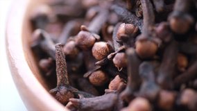 Close up footage of clove spices in a wooden bowl. Panning right. Selective focus.
