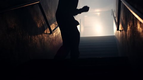 A silhouetted male fighter shadow boxes in a foggy, dimly lit stairwell
