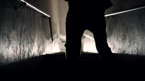 A silhouetted male fighter runs up a set of stairs in a dark room and shadowboxes