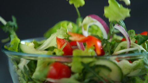 Fresh salad flying to bowl in super slow motion.