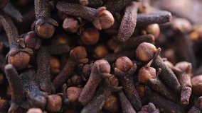 Close up footage of clove spices in wooden bowl. Tilt up shot. Selective focus.