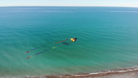 Aerial view of flying kite filmed by a drone in mid air , relaxing aerial flying  kite drone view, wind power ,renewable energy , clean power , clean energy ,air power , recycling energy