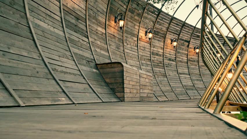 Beautiful girl wearing dress walking on wooden walkway. Woman walks on wooden pier in a summer day.