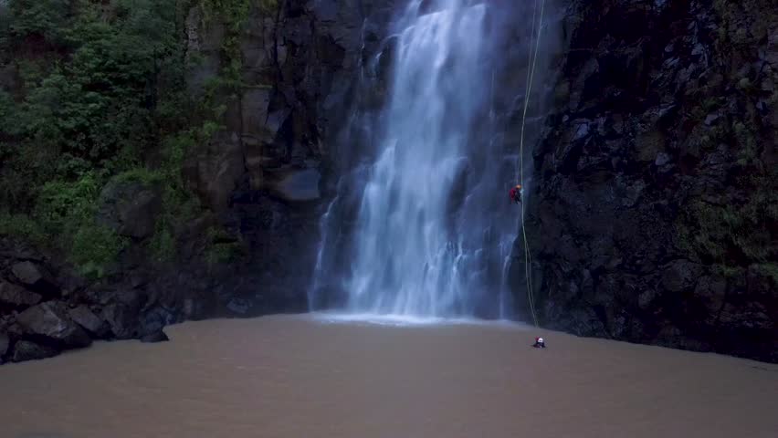 Aerial view of man rappelling waterfall