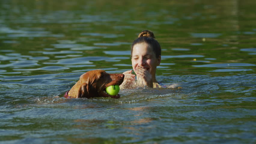 Girl swimming with her brown dog. | Shutterstock HD Video #1022538481