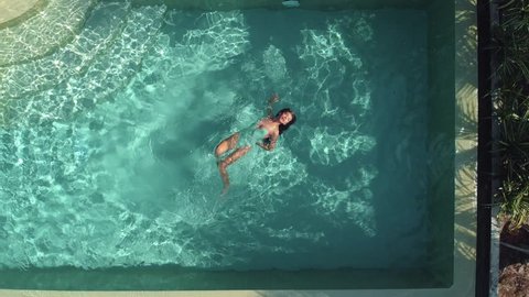 A young glamorous woman in a bikini in a pool in a luxury villa