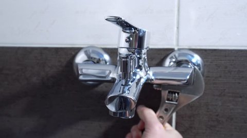 Plumber fixing water tap with a spanner.