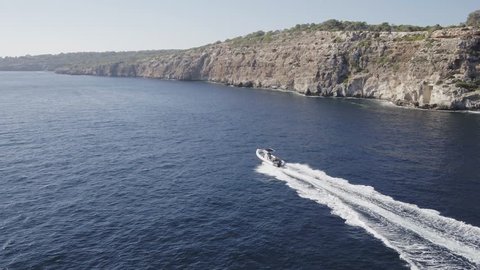 Aerial drone view chasing a very fast rib inflatable pleasure craft on blue ocean with INSPIRE 2 drone.