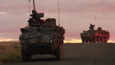 CIRCA 2018 - a convoy of US military vehicles travels at sunset or sunrise in a foreign country.