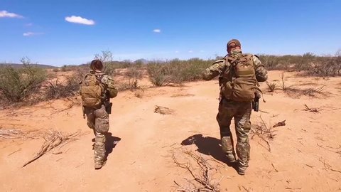 CIRCA 2018 - U.S. Border patrol agents walk the U.S. Mexico border utilizing a K9 canine dog to assist.
