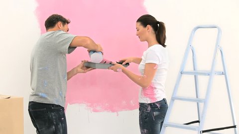 Happy couple painting a wall in pink Stock Video