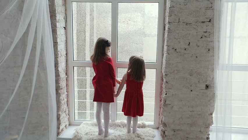 Two girls in red dress near large window