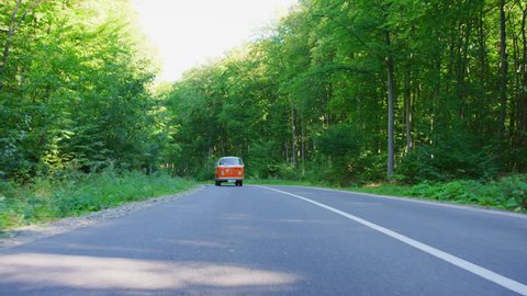 Driving an orange van on an empty road.