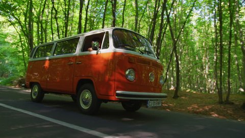 Driving an orange bus on a forest road.