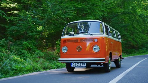Driving an orange campervan on a forest road.