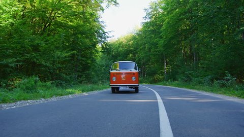 Driving an orange van on a road through a forest.