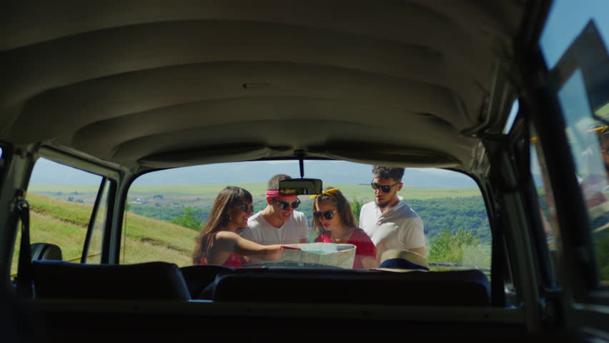 Travellers looking at a map, outside their van. | Shutterstock HD Video #1022576548
