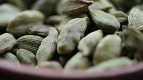 Close footage of cardamom spices in wooden bowl. Tracking shot. Selective focus.