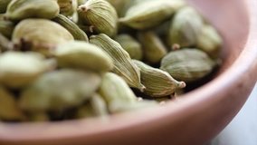 Close up footage of cardamom spices in wooden bowl. Tilt up footage. Selective focus.