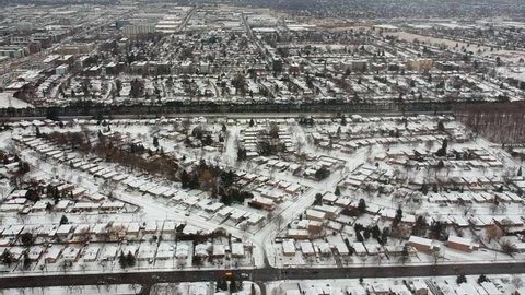 Aerial drone view of roads and houses winter landscape. Winter city streets from a bird eye view. Top perspective of  snow covered buildings. Roads, lawns, cars and trees covered with snow from above.