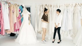 Young wedding dress designer working. Young asian woman measuring her customers body for wedding dress. Small business concept.