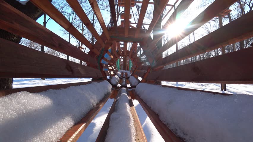 Empty wooden children swings in city park at sunny winter day.