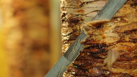 A cook cuts meat to make shawarma, gyros, doner kebab. Cooking meat on a skewer