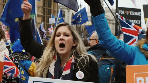 LONDON, circa 2019 - Slow motion shot of a BREXIT supporter holding a flag and banner and passionately defending her views in London, England, UK