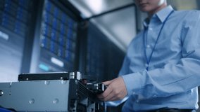 In the Data Center: IT Engineer Installs New HDD Hard Drive and Other Hardware into Server Rack Equipment. IT Specialist Doing Maintenance, Running Diagnostics and Updating Hardware. Low Angle. - Powered by Shutterstock - Get 15% off with code: PIKWIZARD15