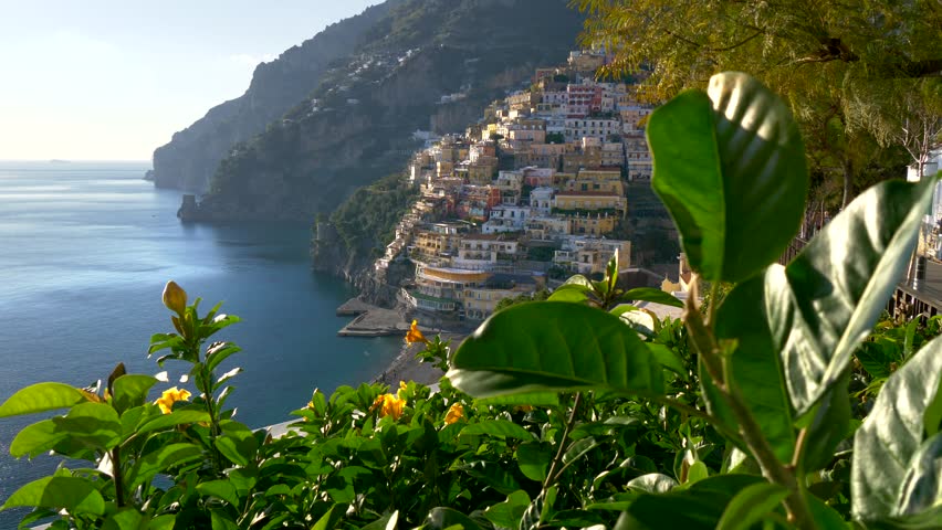 Positano, Amalfi Coast, Salerno, Italy at spring time. Crane shot of Positano village at sunset lights, yellow flowers on foreground. UHD, 4K | Shutterstock HD Video #1022595478