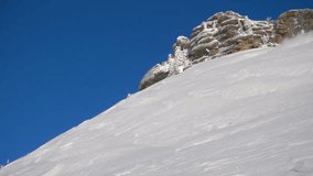 stock video footage. a skier rides down the slope making turns. snow splatter, no trace. on the background of beautiful rocks, blue sky and white snow. camera bottom view. Super slow motion