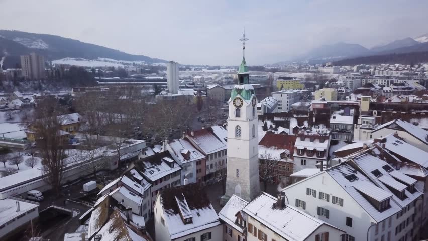 Swiss City Olten during Winter old wooden bridge, medieval tower with fresh snow on rooftops 4k aerial view